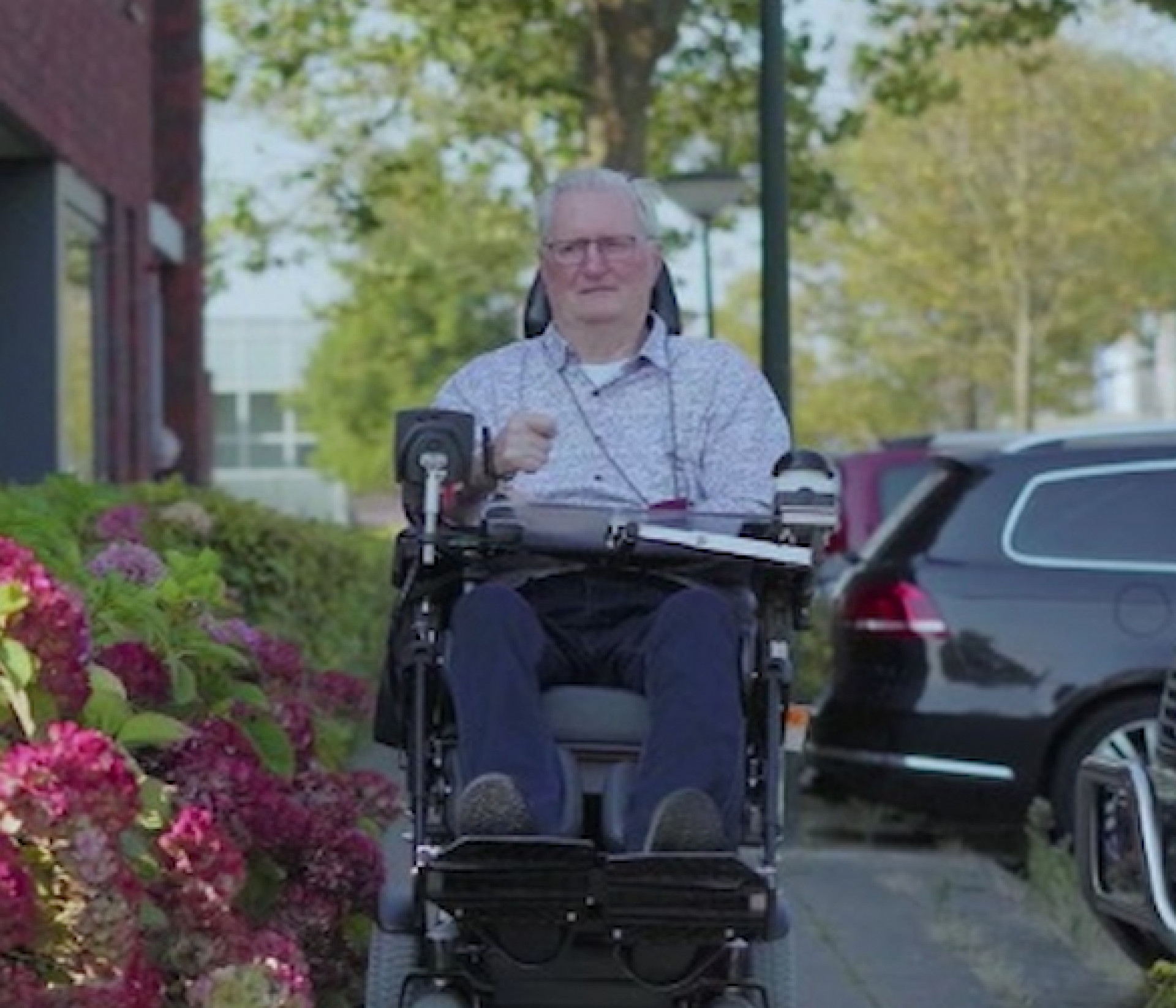 MCL, man in rolstoel naast bloemen op stoep